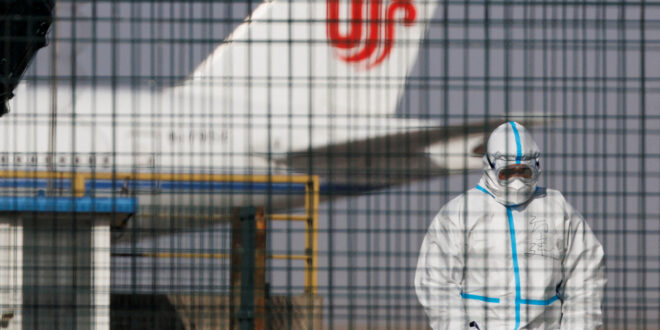 عامل يرتدي بدلة واقية بالقرب من طائرة تابعة لشركة طيران أير تشاينا في مطار بكين في 6 يناير 2023