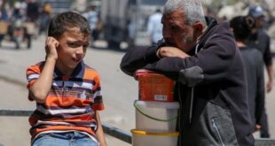 رجل وطفل فلسطينيان ينتظران الحصول على الطعام من مطبخ خيري، في ظل نقص إمدادات المساعدات، بعد أن شنت القوات الإسرائيلية عملية برية وجوية في الجزء الشرقي من رفح، 8 مايو/أيار 2024.