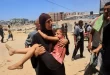 مرأة فلسطينية تحمل طفلاً مصاباً إلى مستشفى ناصر، في خان يونس في 13 يوليو/تموز 2024،  جراء غارة إسرائيلية قتلت ما لا يقل عن 90 شخصاً وأصابت قرابة 300 شخص في مخيم المواصي للاجئين.