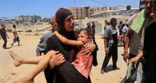 مرأة فلسطينية تحمل طفلاً مصاباً إلى مستشفى ناصر، في خان يونس في 13 يوليو/تموز 2024،  جراء غارة إسرائيلية قتلت ما لا يقل عن 90 شخصاً وأصابت قرابة 300 شخص في مخيم المواصي للاجئين.